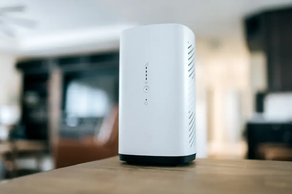 A close-up shot of a white AT&T Internet Air gateway standing on a wooden surface with a blurred living room in the background.