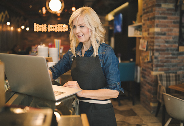 Coffee shop owner working on laptop