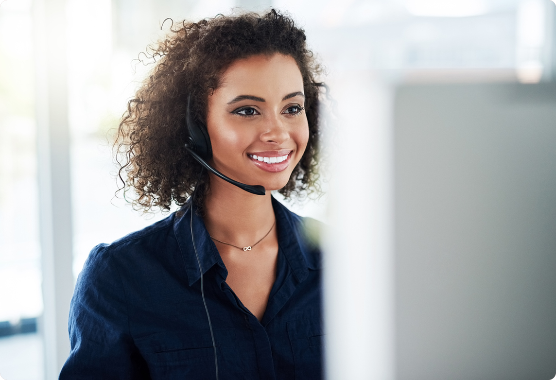 Customer service rep smiles while working at computer.
