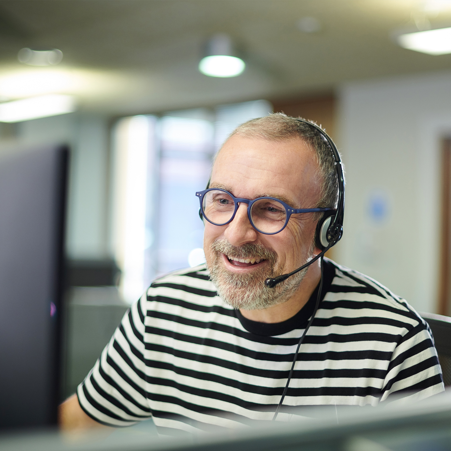 customer service agent in a headset and wearing a black and white striped shirt
