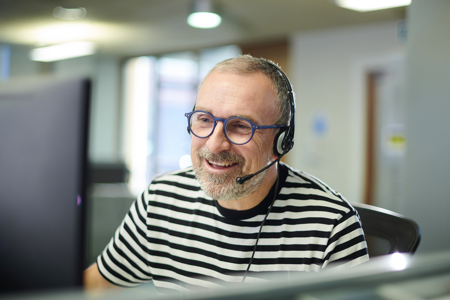 customer service agent in a headset and wearing a black and white striped shirt
