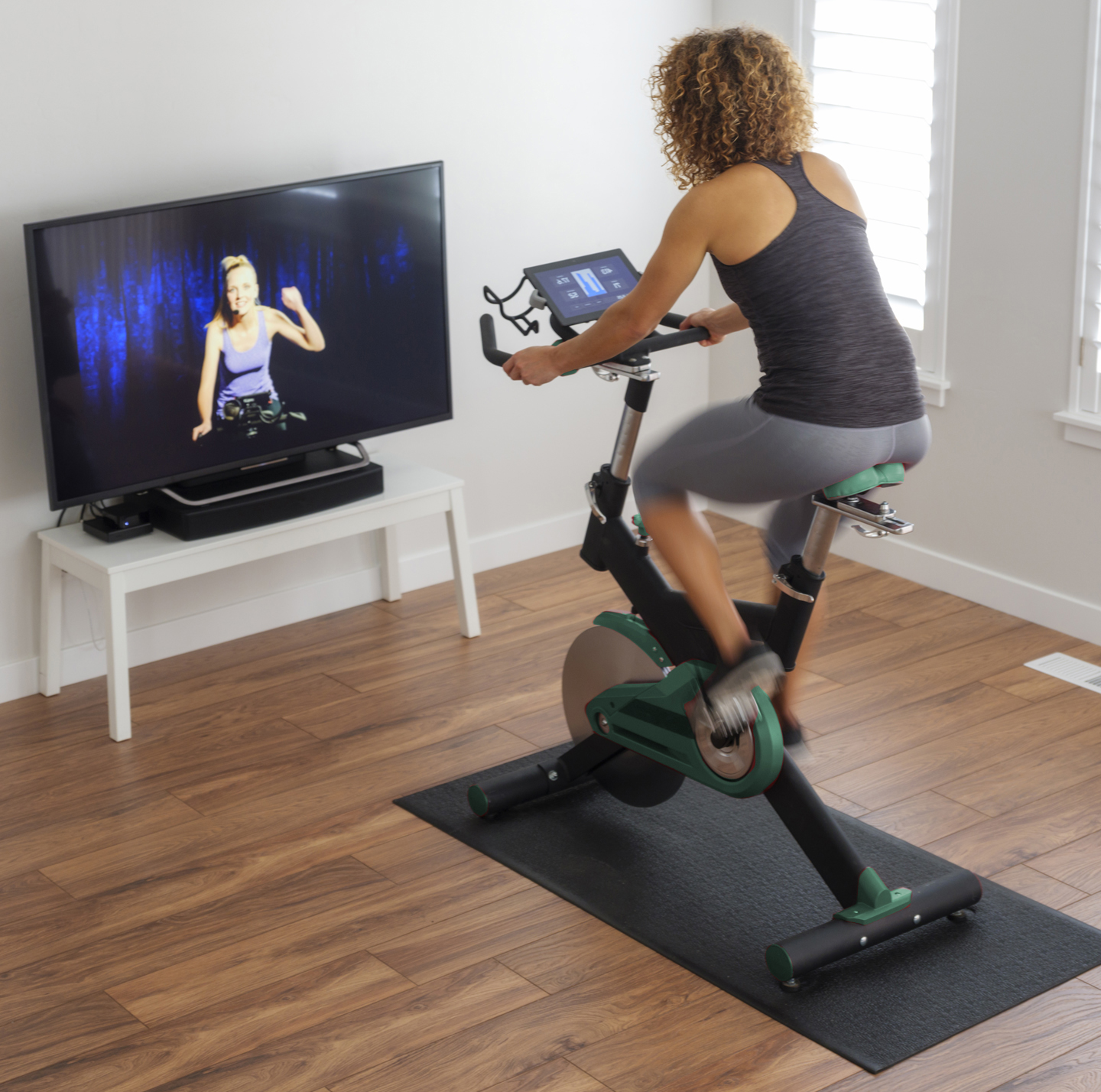 Mujer montando bicicleta estática y transmitiendo su clase de bicicleta estática. Woman riding exercise bike and streaming her exercise bike class.