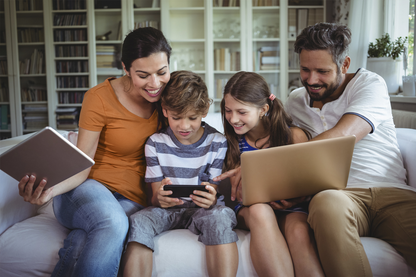 Family on the sofa enjoying time together on their devices