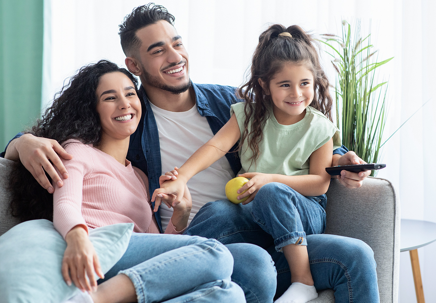 Parents and their little daughter watching tv at home