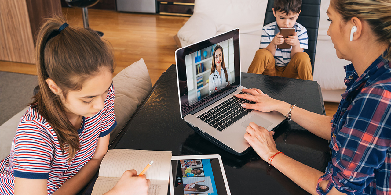 mother and two children sitting at table, using devices
