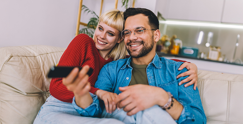Happy couple watches tv at home.