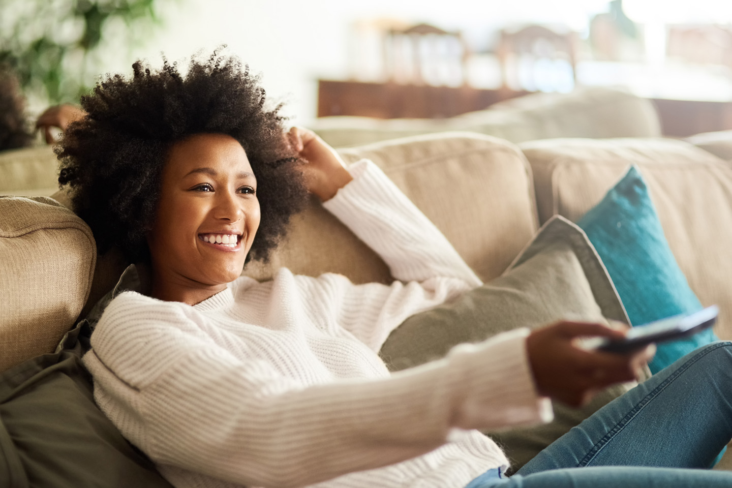 Smiling Girl watching TV on her sofa.