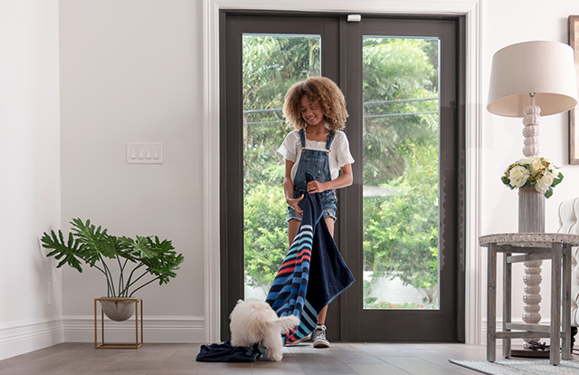 Girl playing with dog, in front of a door with a door sensor