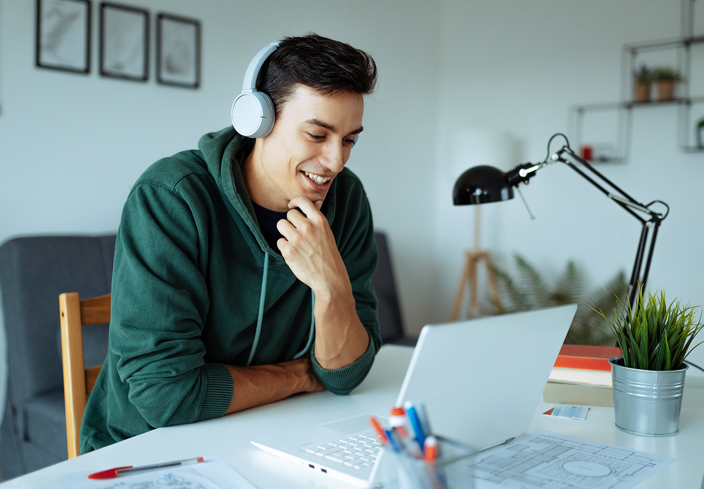 Man sitting at desk wearing headphones looking at laptop