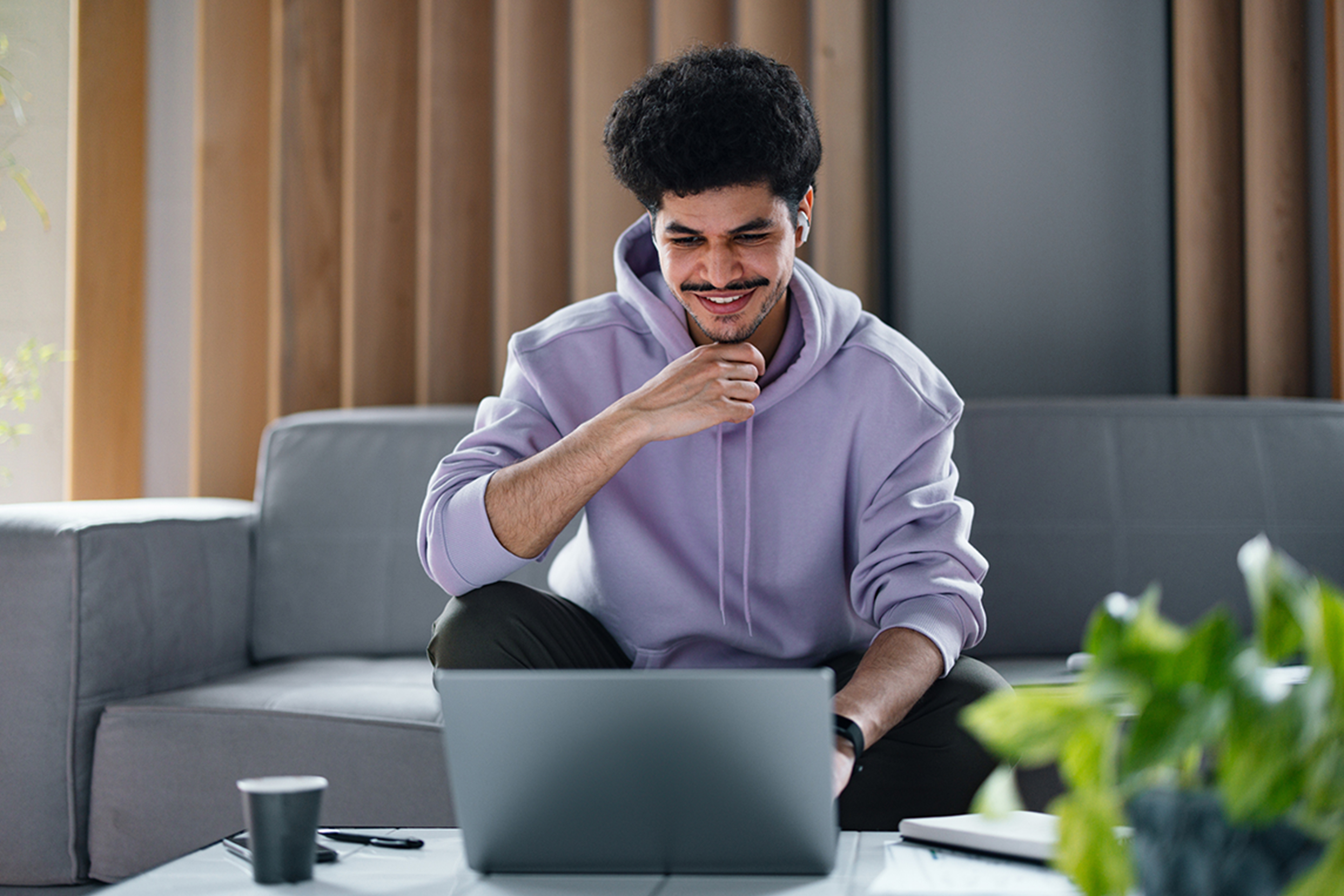 Man wears purple hoodie and uses laptop with fast internet at home.