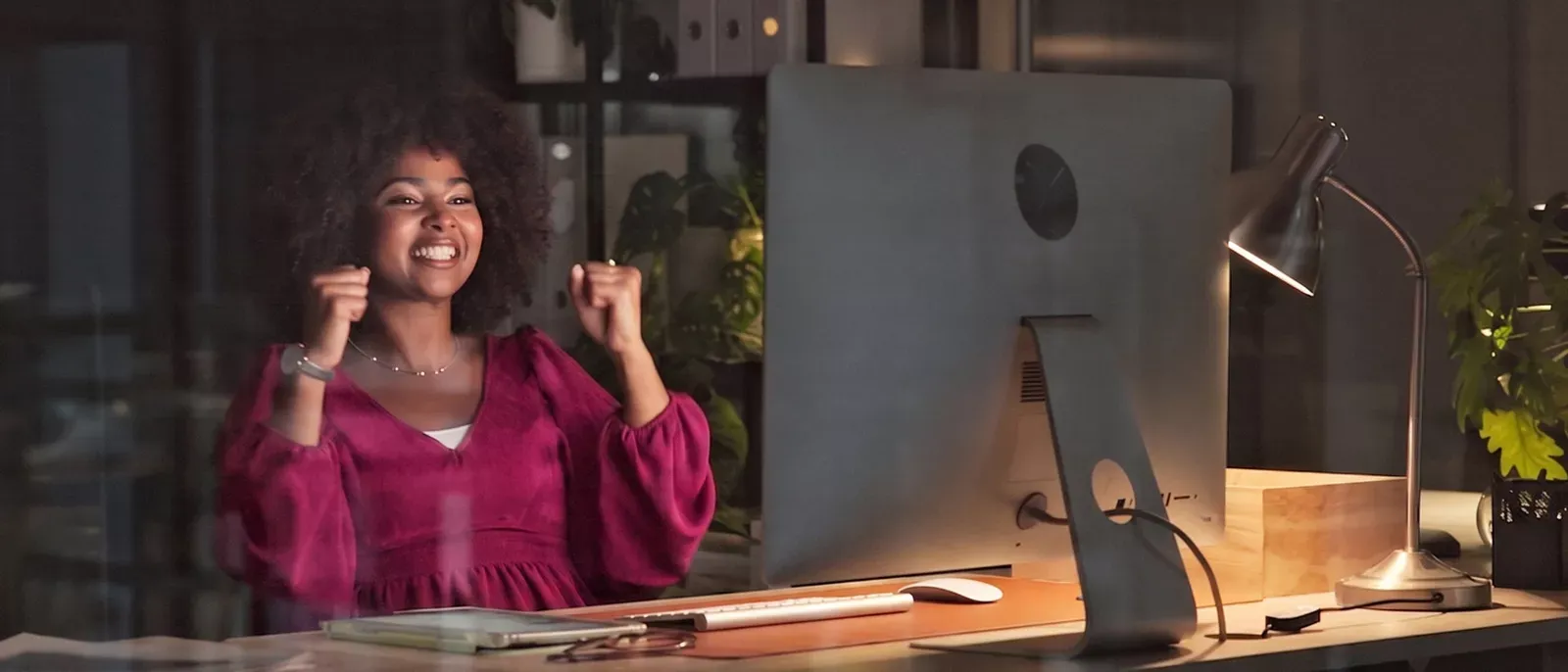 Woman sitting at desktop computer celebrating her internet speed.