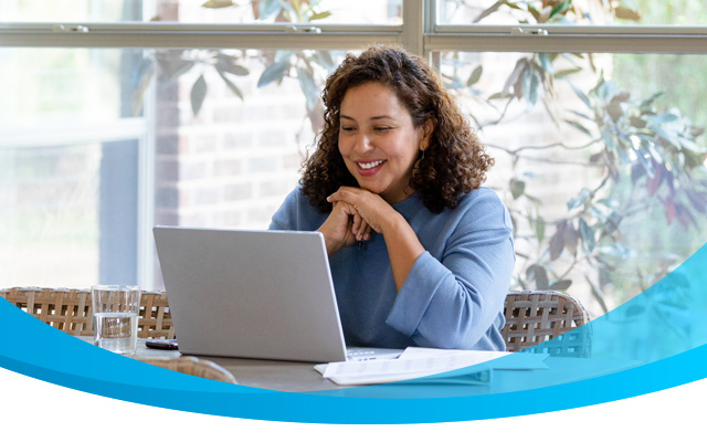 Smiling woman using the internet on her laptop.