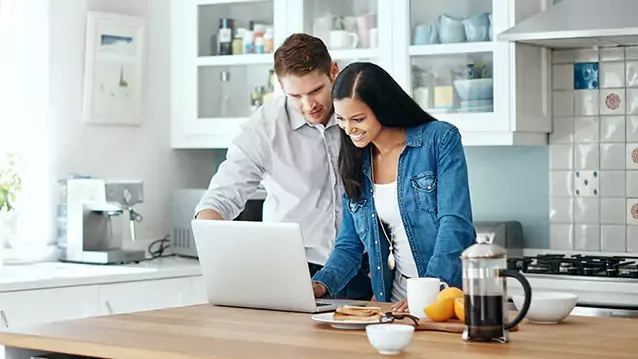 a couple using laptop in kitchen