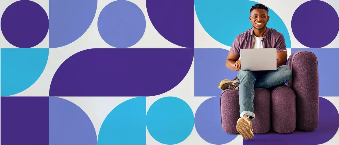 Smiling man with his laptop sitting on a plush seat, in front of an abstract shaped background.