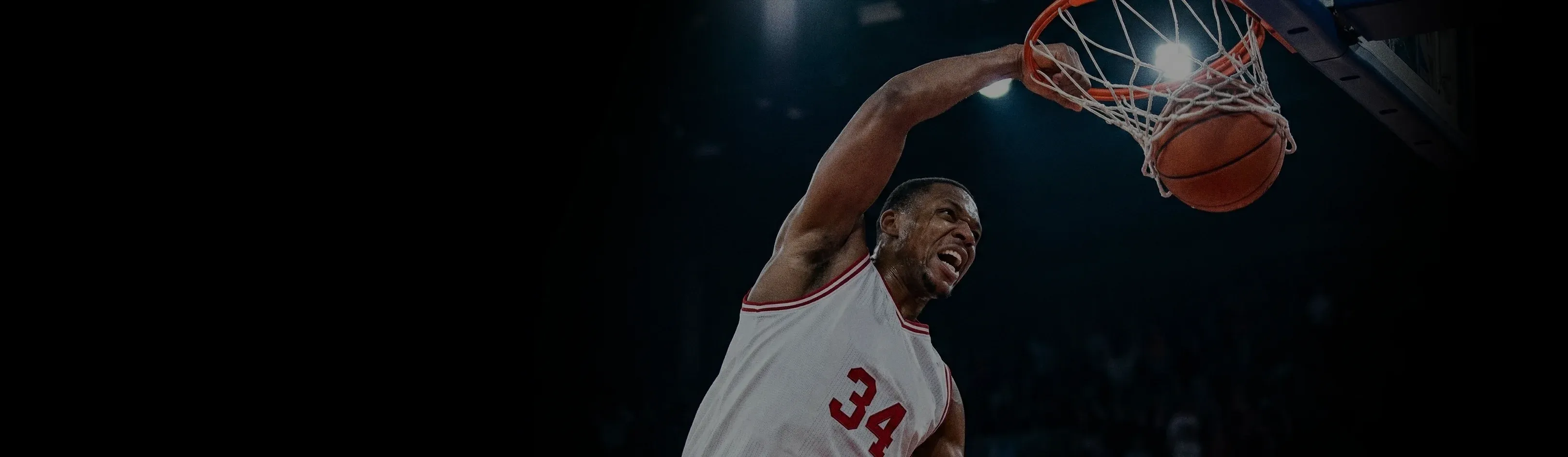 A basketball player in a white jersey with the number 34 performing a powerful slam dunk.