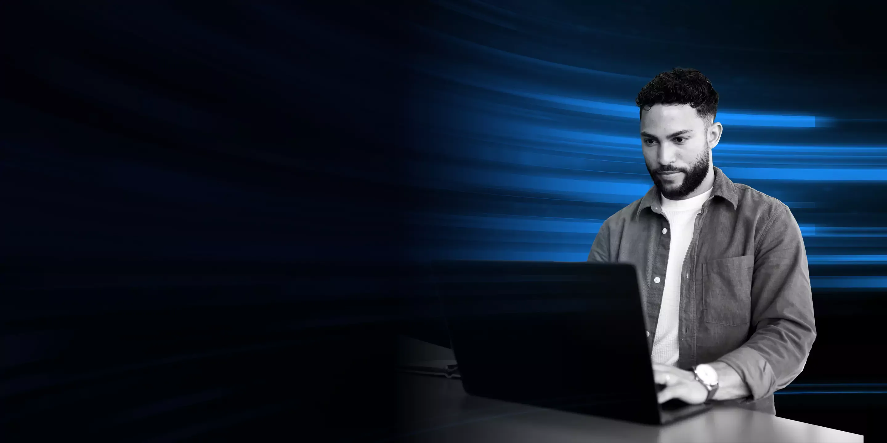 Man using laptop in front of a blue light flashes.