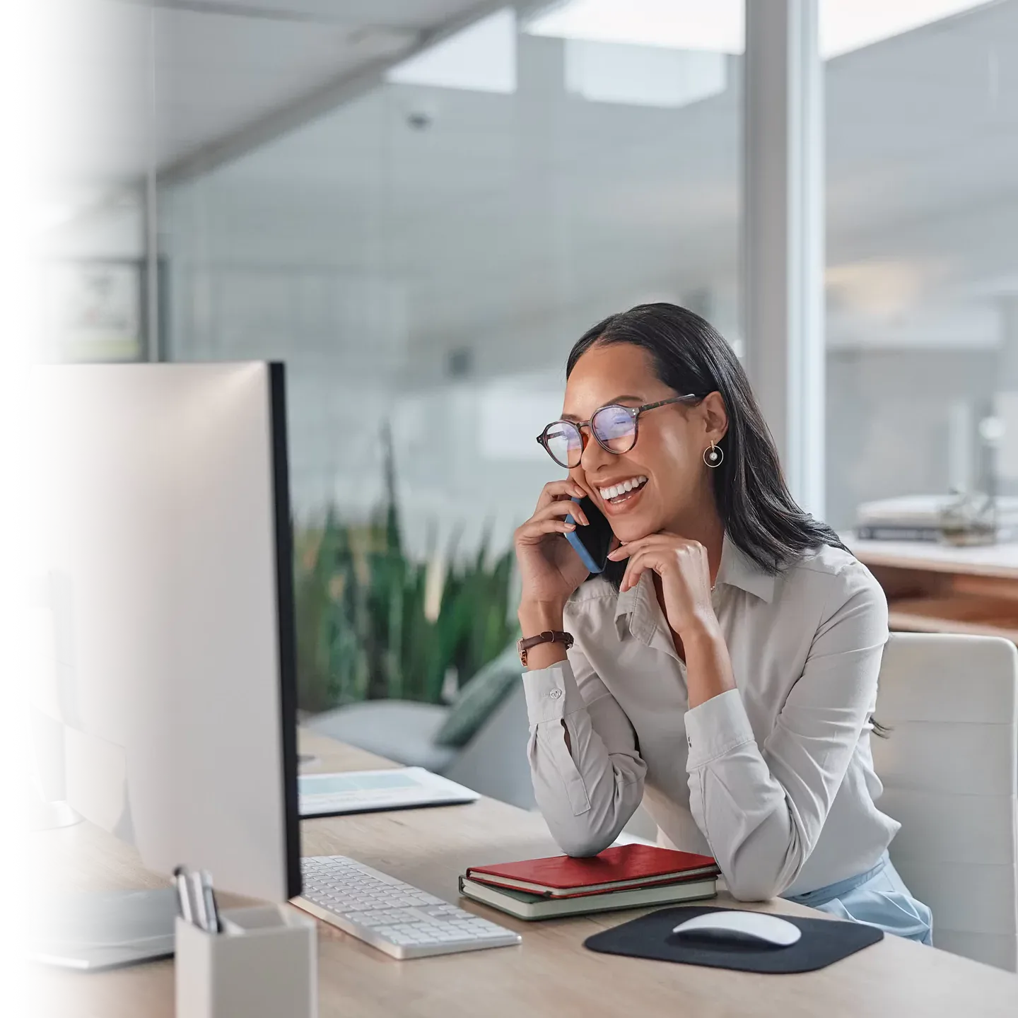 Smiling office worker talking on her phone and using her internet.