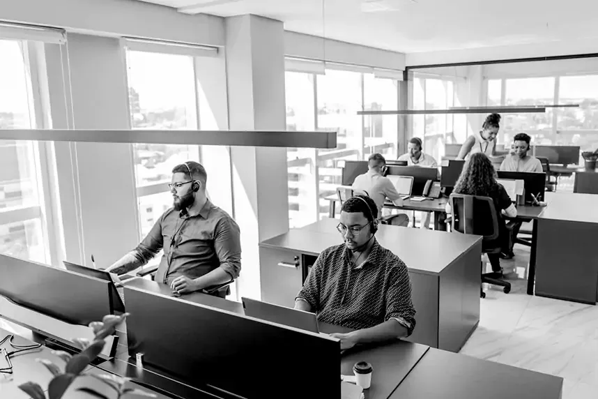 A team of well dressed professionals wearing headsets sitting at call center desks