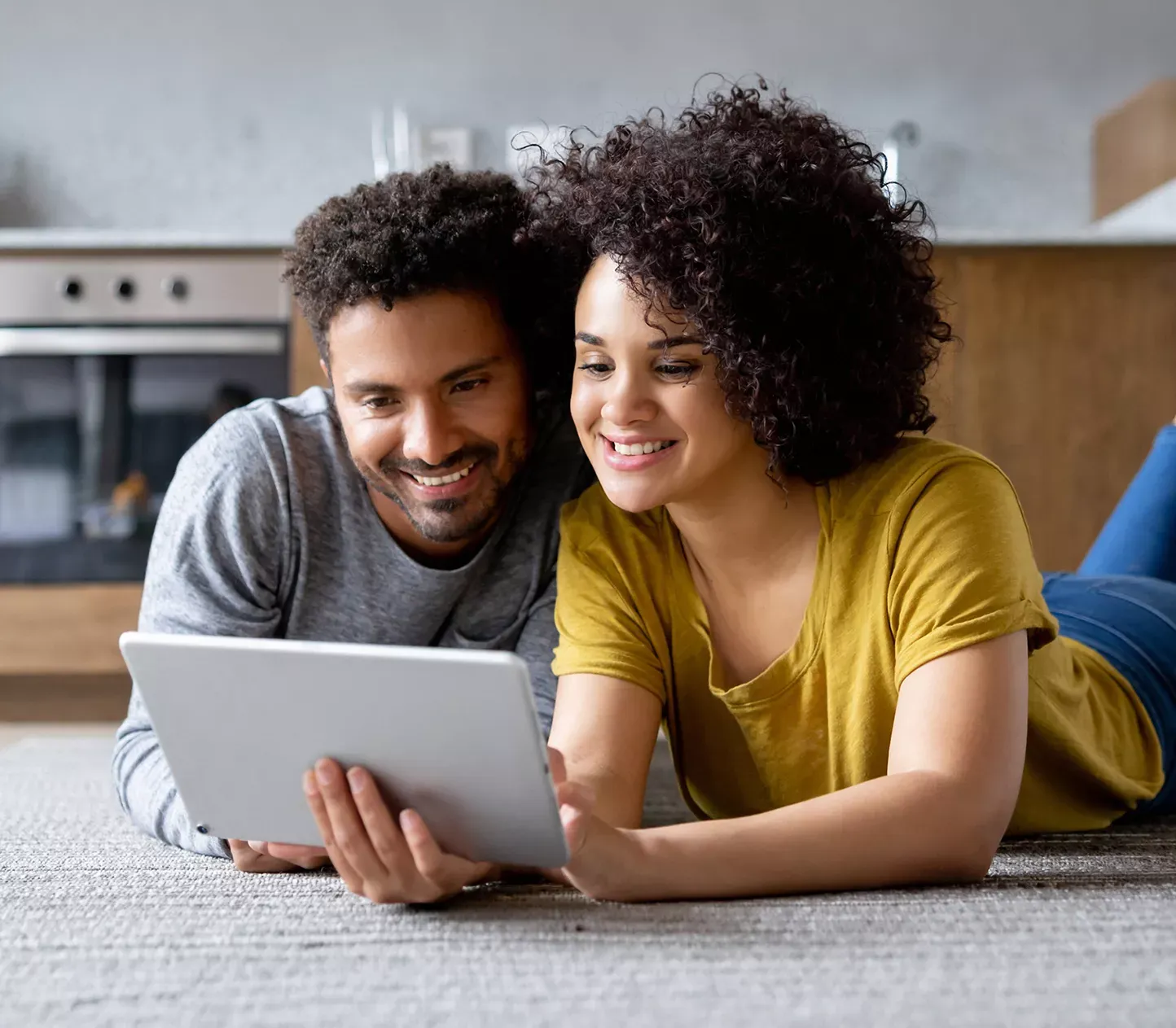 Couple with fast internet laying on floor looking at tablet together