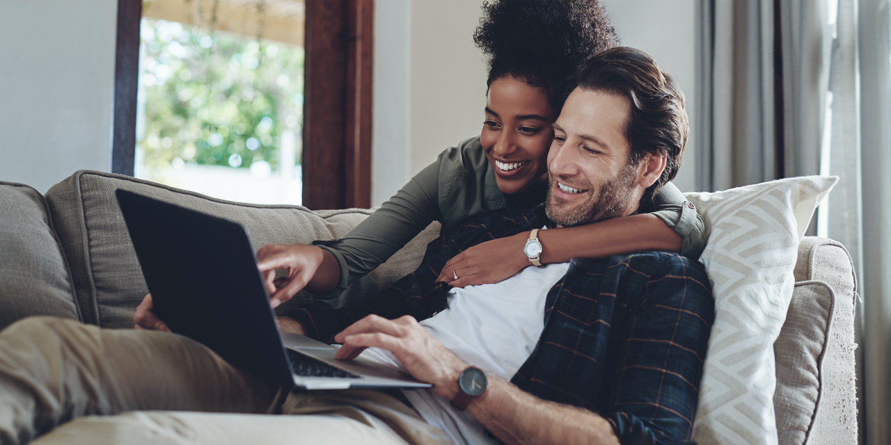 a couple on the couch using CenturyLink internet on a laptop