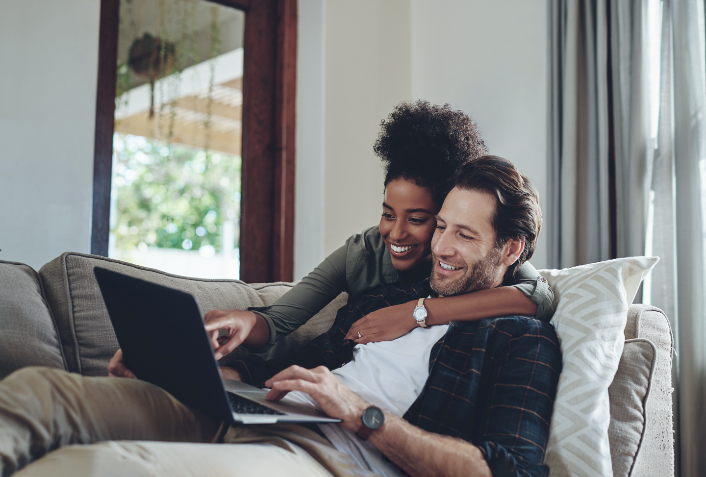 a couple on the couch using CenturyLink internet on a laptop