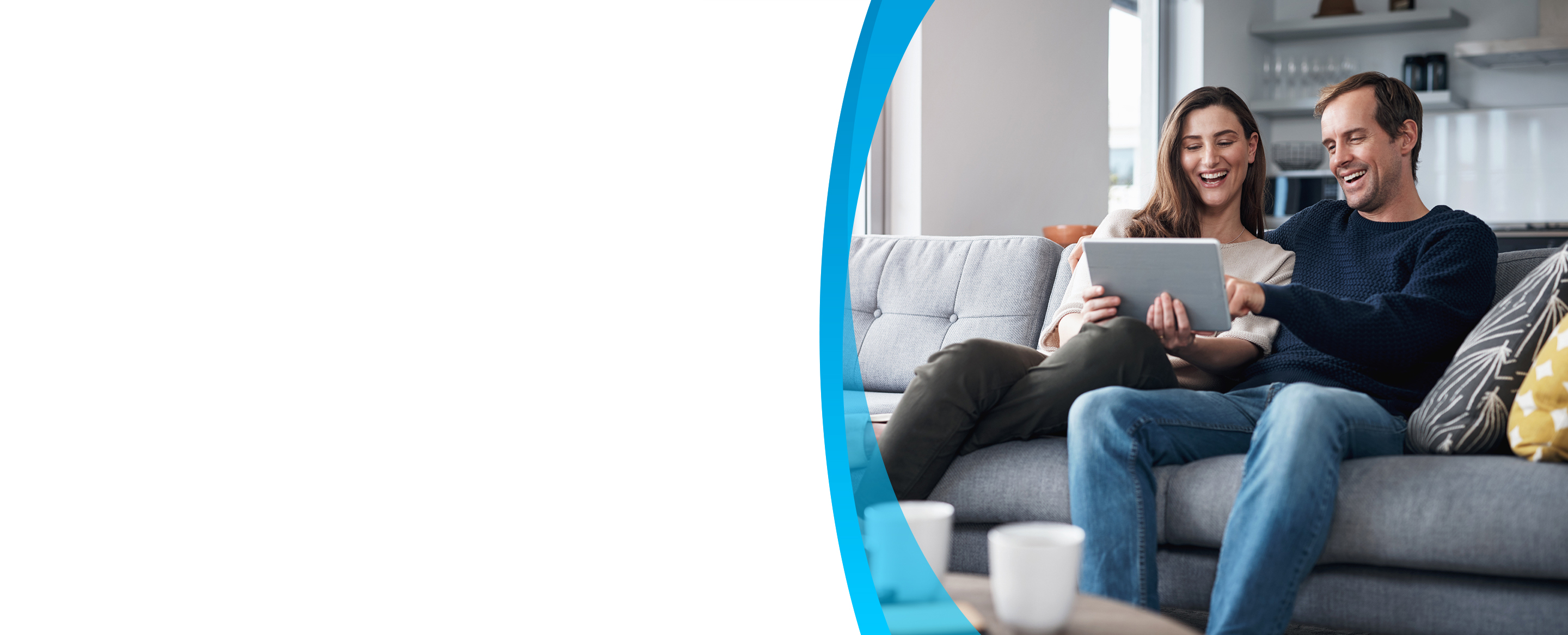 couple sitting on the sofa together and using a tablet