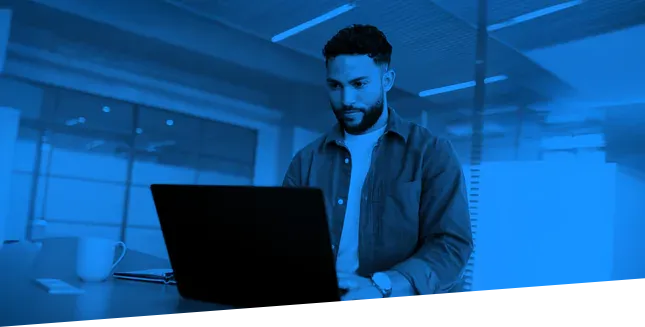 Man wearing a collared shirt sitting at a desk with a computer.