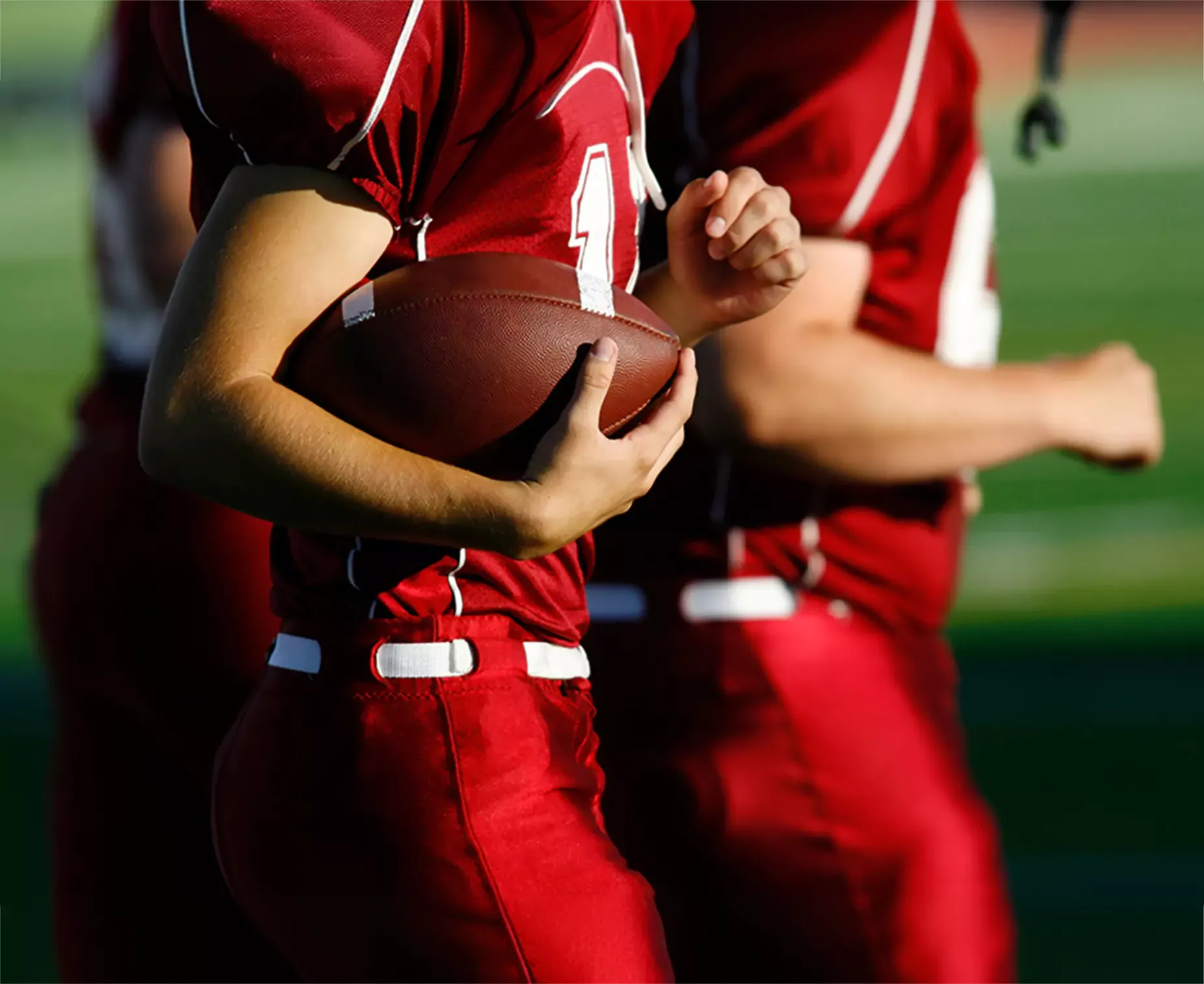 Closeup of college football players holding football.