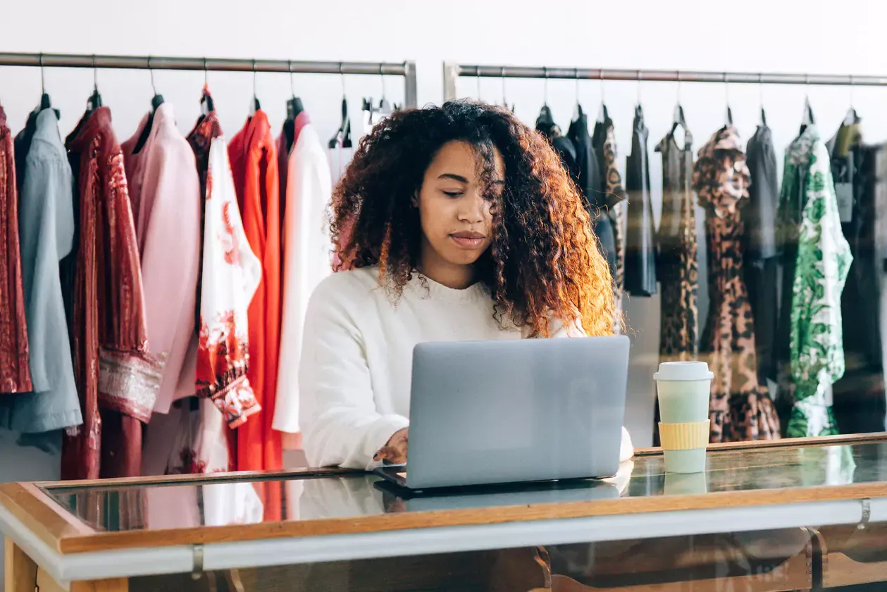 Small business owner working on computer in her clothing shop