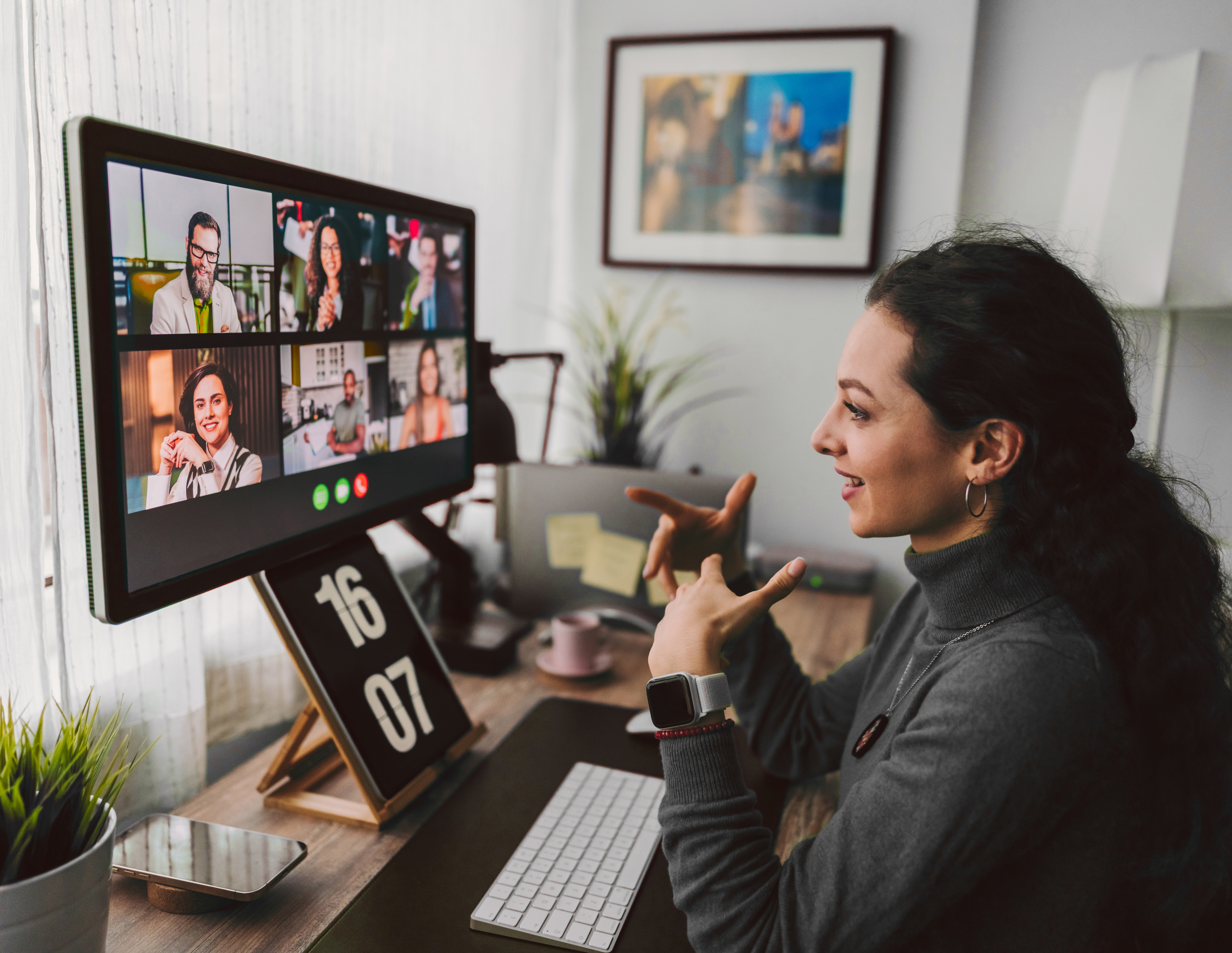 Woman working from home, and talking to co-workers on a video call.