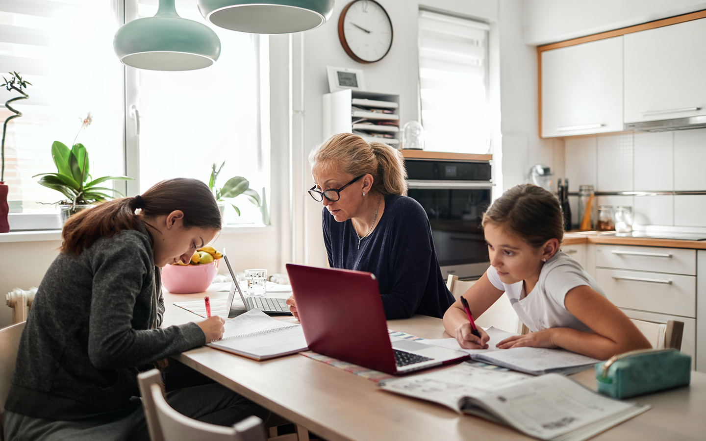 Family at a kitchen table using CenturyLink internet to do homework.