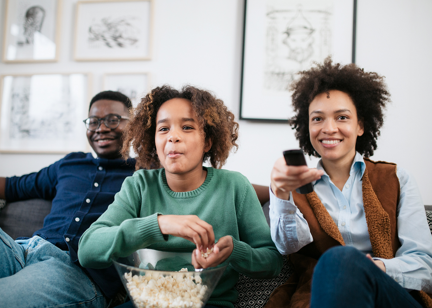 A family watching a movie and sharing popcorn