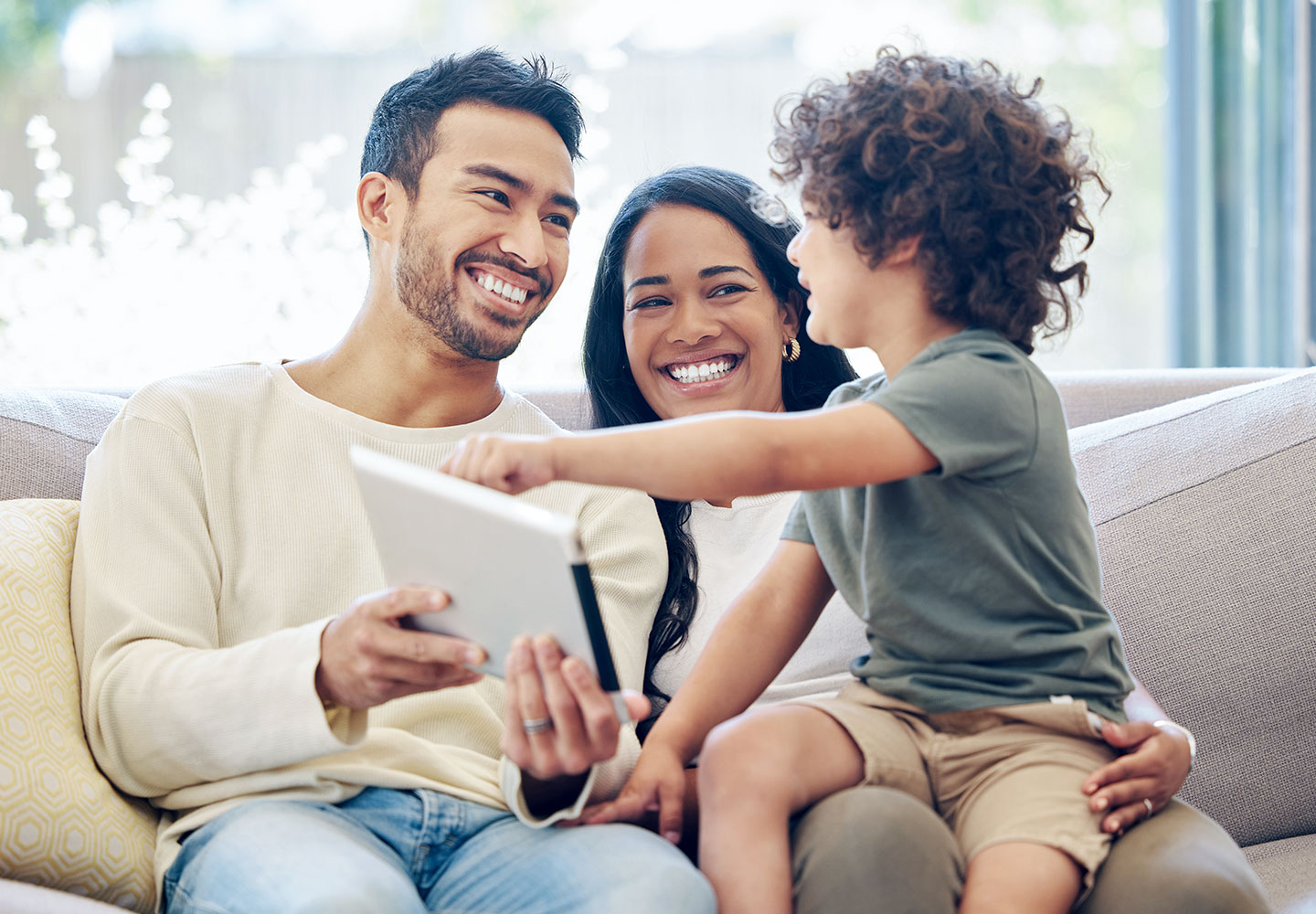 Child sitting with his family on a sofa looking at a tablet