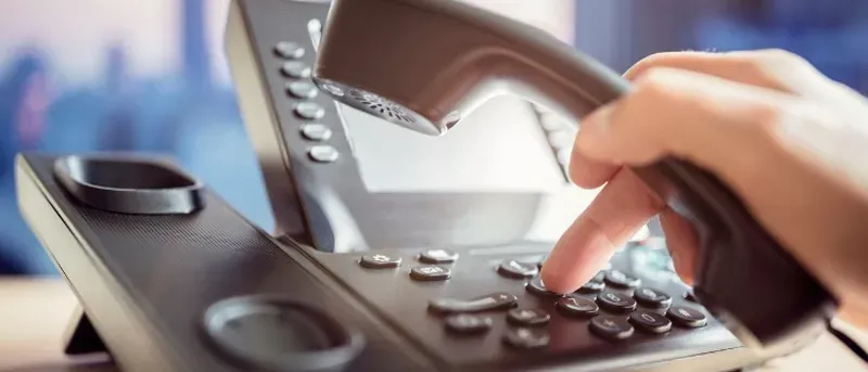 Close up image of a person using their office phone.