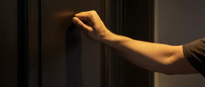 A hand knocking on a door.
