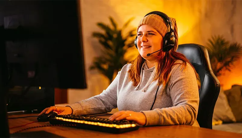 Happy woman wearing beanie games on a computer at home