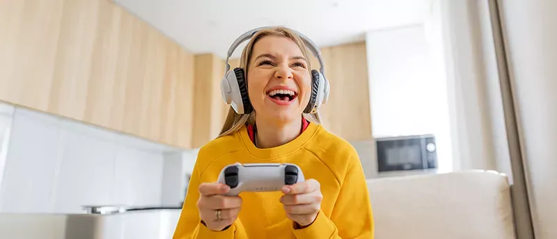 Happy woman plays video games at home with fast fiber internet