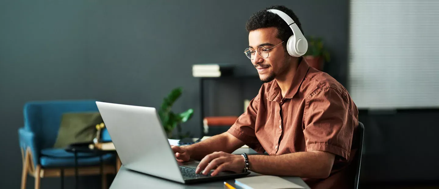 Man enjoying is fast fiber internet and listening to music on his wireless headphones.