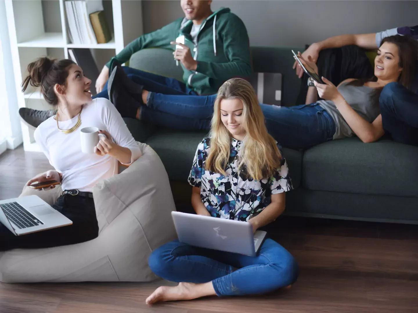 Group of friends using different devices in their apartment.