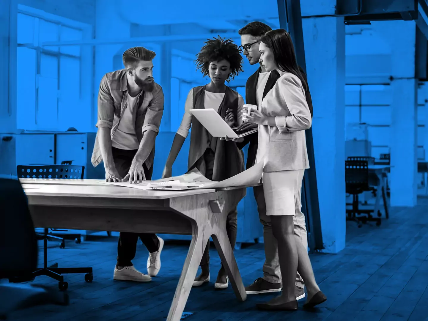 A group of office workers collaborating around a laptop.