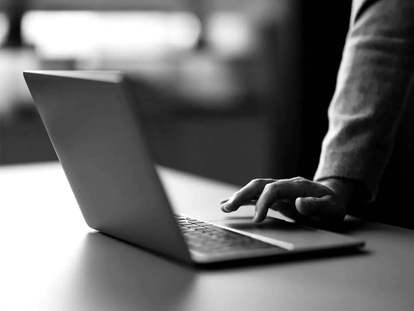 A hand on a laptop trackpad.