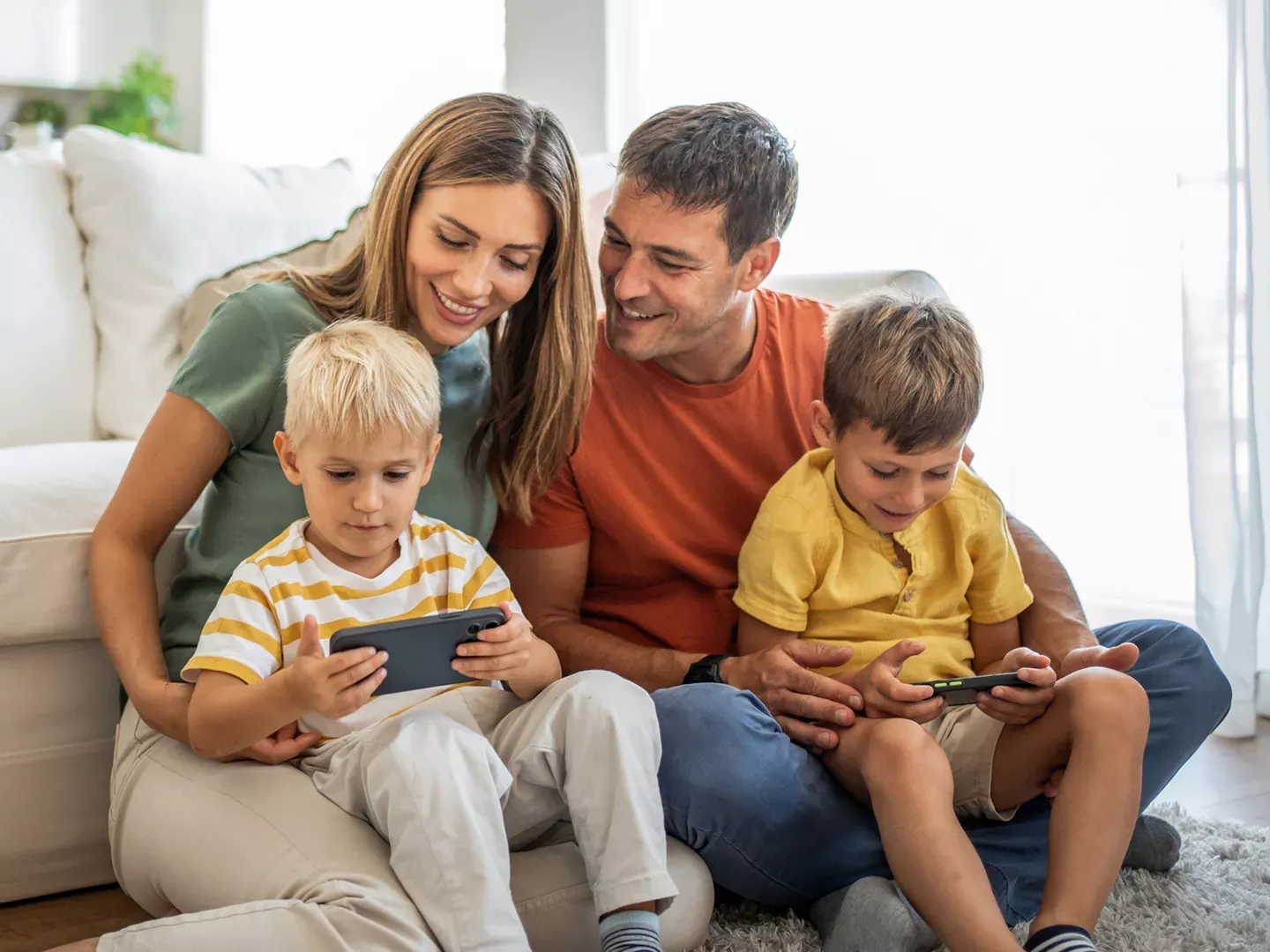 Happy family uses internet devices while sitting in living room