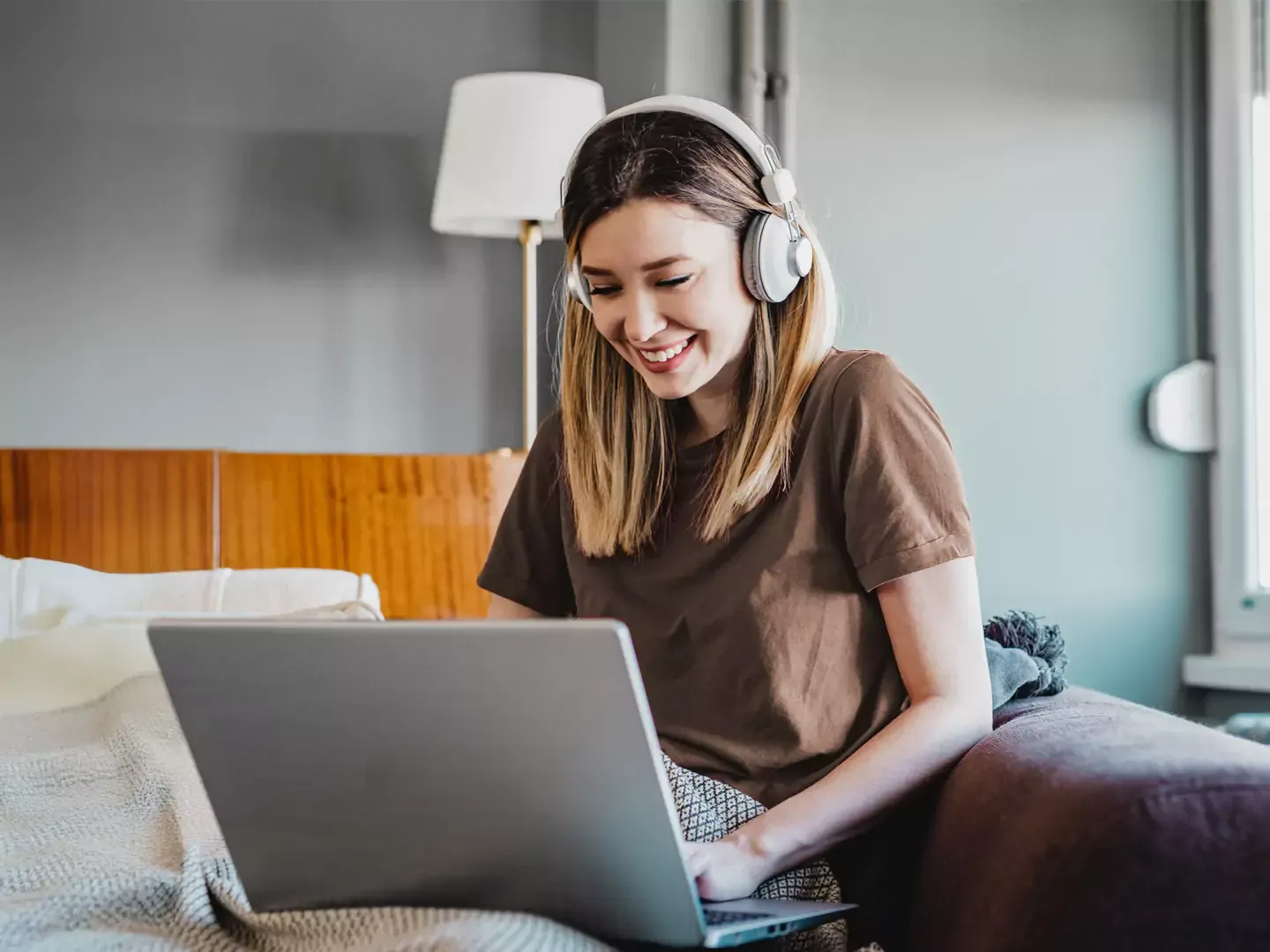 Woman listening to headphones, and using her computer.