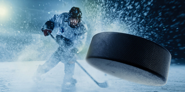 Hockey player hitting puck on the ice