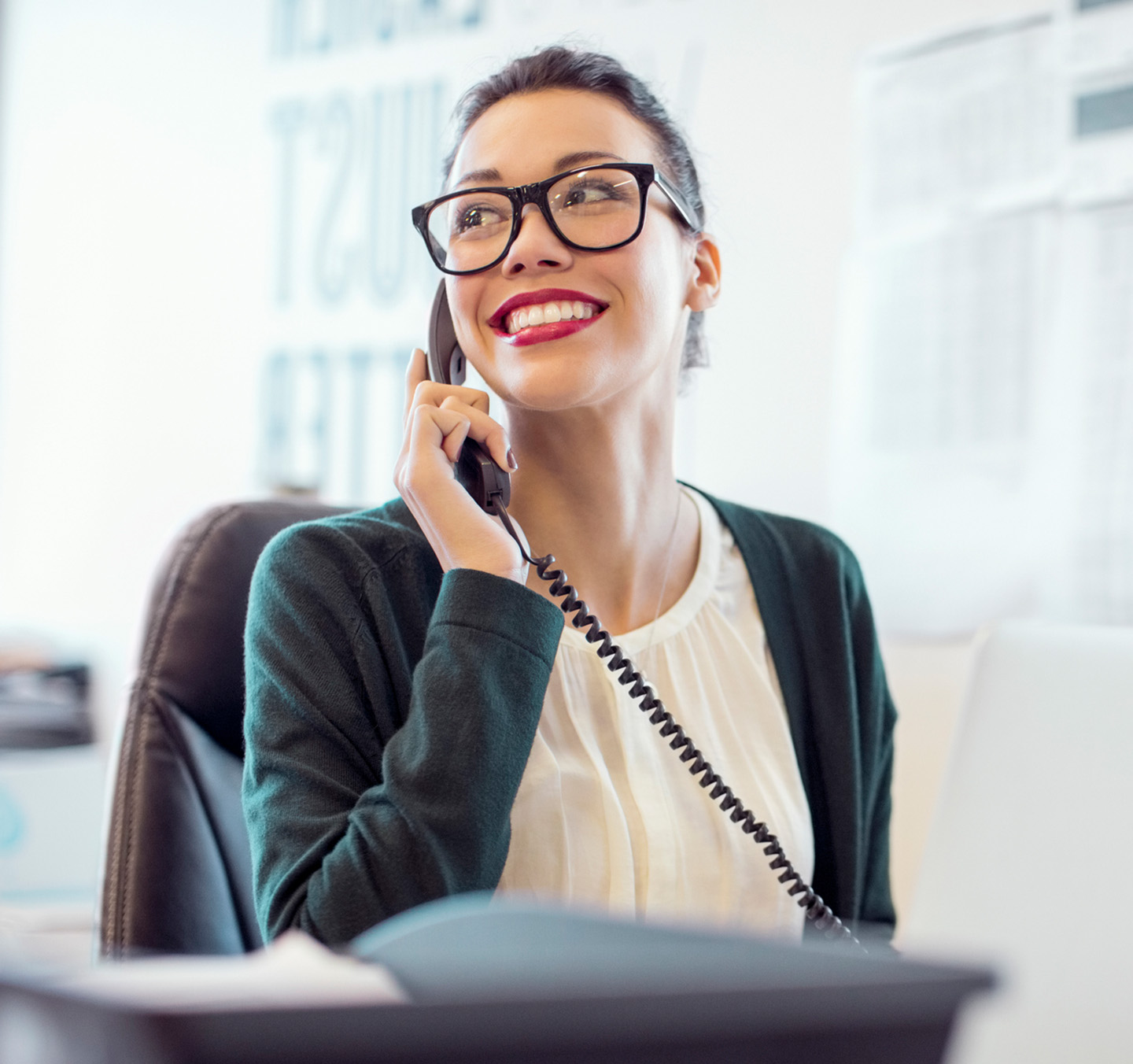 Happy woman talks on business phone at work.