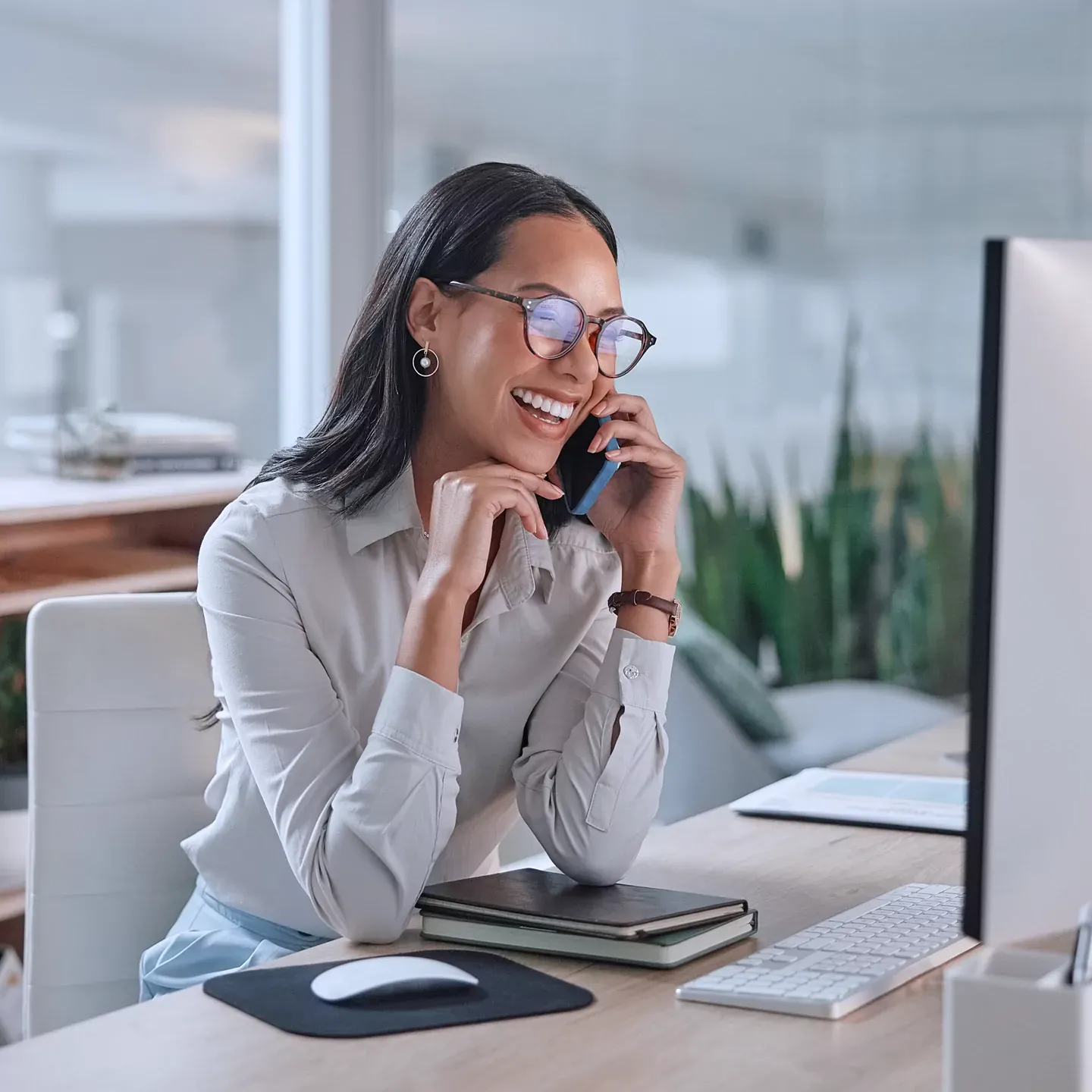 Woman smiling talking on the phone and using computer in the home office.