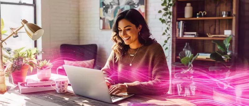 Woman in her home office working, with neon magenta lights representing fiber fast speeds.
