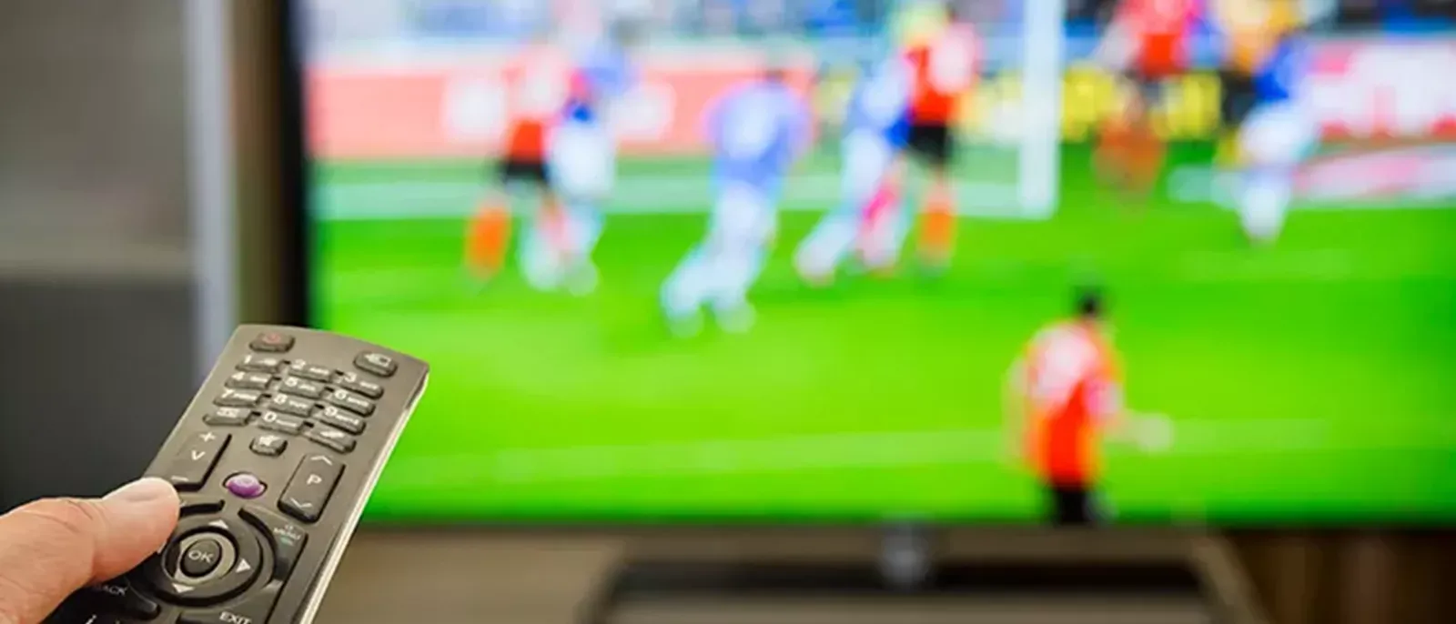 Remote control pointed towards tv with soccer playing