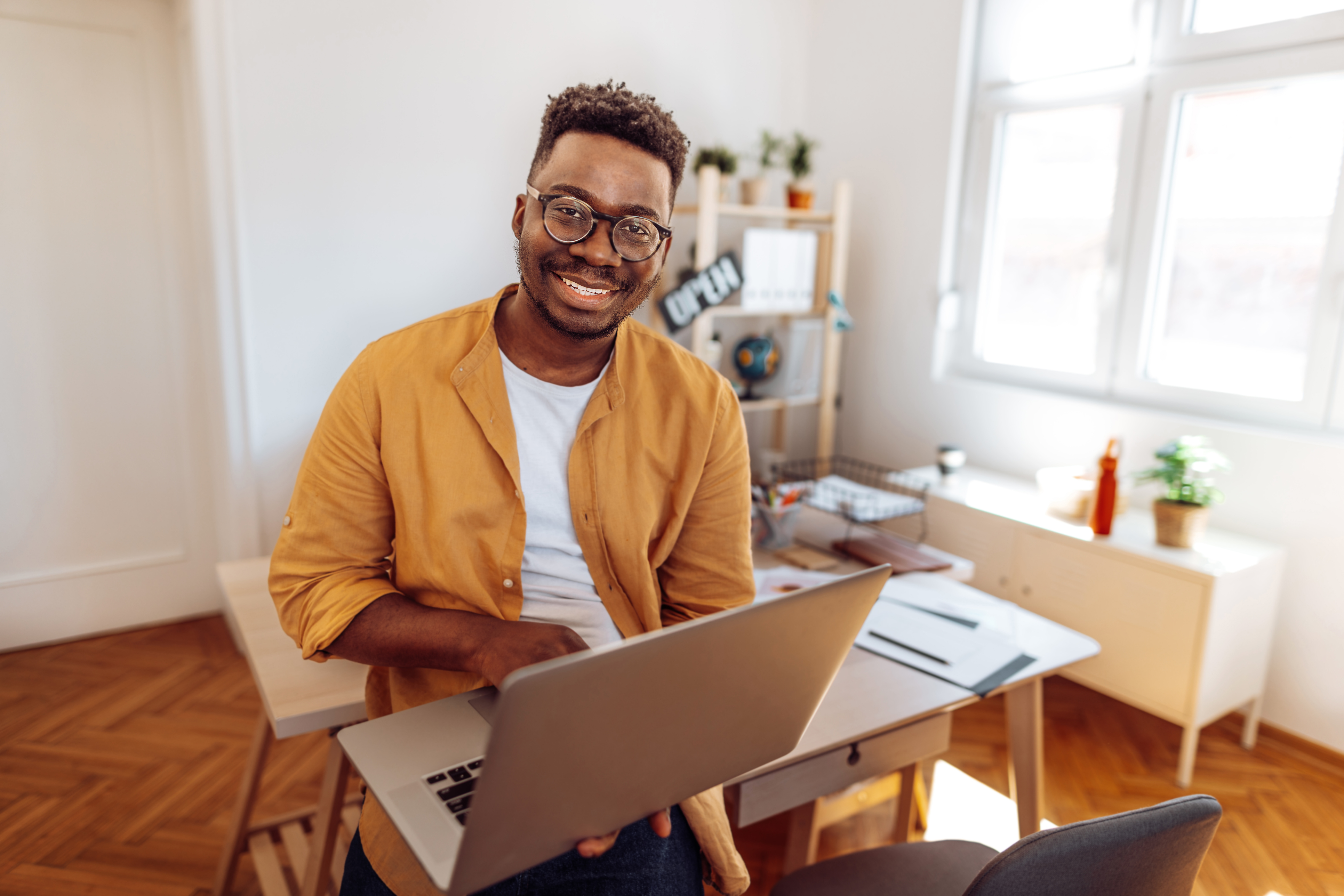 Happy young man working on a laptop inside a home office