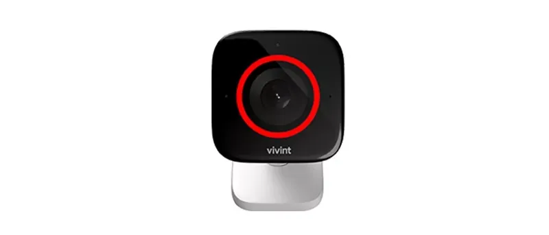 A close-up of the Vivint Outdoor Camera Pro, a small black square camera with a lens encircled by a red light, on a silver base.